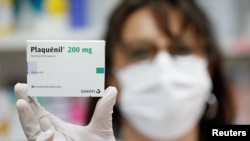 A pharmacist displays a box of Plaquenil antimalarial tablets in this illustration picture