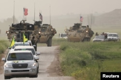 FILE - Kurdish fighters from the People's Protection Units (YPG) head a convoy of U.S military vehicles in the town of Darbasiya next to the Turkish border, Syria, Apr. 28, 2017.