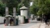 FILE - A policeman (2nd R) and private security personnel stand guard at the entrance of a road leading towards the U.S. consulate in Lahore.