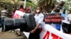A Kenyan journalist carries a giant plastic replica of a camera as he participates in a protest along the streets of the capital Nairobi, Dec. 3, 2013. 