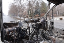 Una fotografía tomada el 7 de enero de 2022 muestra un automóvil incendiado cerca de un edificio administrativo en el centro de Almaty, luego de que estalló la violencia luego de las protestas por las alzas en los precios del combustible.