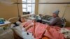 Una conocida visita un hospital y se sienta junto a Marina Klimenko, de 28 años, y Lyudmila Antonenko, de 46, trabajadoras heridas en un mercado que recientemente fue atacado por bombardeos en Donetsk, Ucrania, controlada por Rusia, 22 de enero de 2024. 