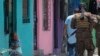 Una anciana observa cómo los soldados patrullan en la comunidad de San José del Pino en Santa Tecla, El Salvador, el miércoles 6 de abril de 2022, durante la represión sin precedentes del gobierno contra las pandillas.