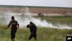 Manaifestantes palestinos huyen de gases lacrimógenos usados por soldados israelíes durante manifestaciones cerca de la frontera entre la Franja de Gaza e Israel, el viernes, 30 de marzo, de 2018.
