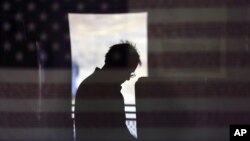 FILE - A voter is reflected in an image of a U.S. flag, as he casts his ballot on Election Day in Jamul, California, Nov. 6, 2012. 