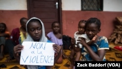 FILE - A young displaced Muslim girl holds a sign saying “No to Violence” at a displaced persons site, the Catholic church in Bangassou, Central African Republic.
