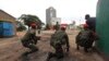 Congolese security officers position themselves as they secure the street near the state television headquarters (C) in the capital Kinshasa, DRC, Dec. 30, 2013.
