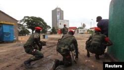 Congolese security officers position themselves as they secure the street near the state television headquarters (C) in the capital Kinshasa, DRC, Dec. 30, 2013.