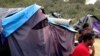 FILE - People sit by a tent at a makeshift camp in Calais, northern France, Sept. 7, 2014.