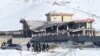 Afghan men stand in front of a collapsed building of a military base after a car bomb attack in Maidan Wardak, Afghanistan, Jan. 21, 2019. 