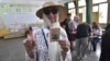 A voter poses for a photo with her inked finger after casting her ballot inside a polling station during the presidential elections in Algiers, Algeria, Sept. 7, 2024.