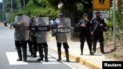 FILE - Nicaraguan police officers block journalists working outside the house of opposition leader Cristiana Chamorro after prosecutors sought her arrest for money laundering and other crimes, in Managua, Nicaragua, June 2, 2021.