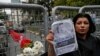 Sahar Zeki, an activist and a friend of slain Saudi writer Jamal Khashoggi, holds a picture of him, after attaching a bouquet of flowers, at the barriers blocking the road leading to the Saudi Arabia's consulate in Istanbul, Tuesday, Oct. 23, 2018. 