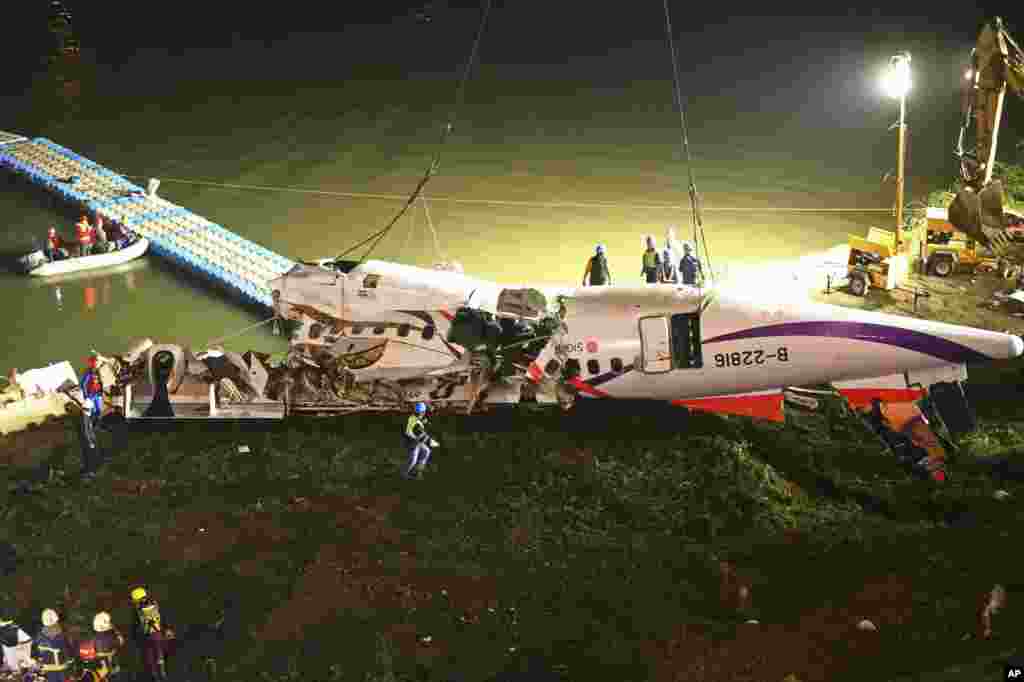 The mangled fuselage of a TransAsia Airways commercial plane is dragged to the river bank after it crashed in Taipei, Taiwan.