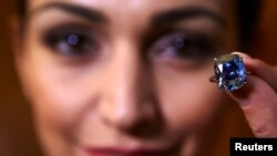 A model poses with a 12.03-carat cushion-shaped blue diamond mounted on a ring at Sotheby's auction house in Geneva, Nov. 4, 2015.