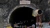 Members of rescue teams stand at the entrance of a tunnel where road workers are trapped after a portion of the tunnel collapsed in Uttarkashi
