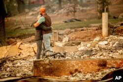 Chris y Nancy Brown se abrazan mientras buscan entre los restos de su casa destruida por el incendio Camp Fire, en Paradise, California, el lunes 12 de noviembre de 2018. A medida que se acercaba el fuego, Nancy Brown escapó de la casa con su hija de dos años y tres perros.