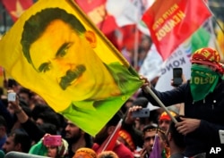 FILE - In this file photo dated March 21, 2018, a youth holds a flag with the image of Abdullah Ocalan, the jailed leader of the rebel Kurdistan Workers' Party, or PKK, in Istanbul, Turkey.