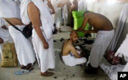 Peregrinos musulmanes hacen fila mientras esperan afeitarse la cabeza de forma gratuita después de arrojar piedras a un pilar que simboliza la lapidación de Satanás, en el primer día de Eid al-Adha, al final de la peregrinación anual del haj. Agosto 11 de 2019. AP foto.
