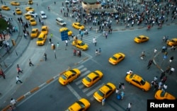 FILE - Yellow taxis pass people standing in silence during a protest at Taksim Square in Istanbul.