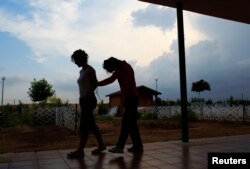 FILE - A deaf-blind woman (R) is led by a caregiver at Santa Angela de la Cruz Center in Salteras, near Seville, Spain, June 6, 2011.
