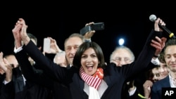 French Socialist Party deputy mayor of Paris, Anne Hidalgo, center, smiles, as outgoing mayor Bertrand Delanoe, stands behind her, during a speech after results were announced in the second round of the French municipal elections, in Paris, March 30, 2014.
