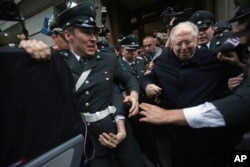 Fernando Karadima es escoltado fuera de la corte luego de testificar en un caso que tres víctimas de pederastia presentaron contra la Iglesia Católica en Santiago, Chile. Nov. 11 de 2015.