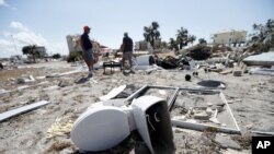 Los vecinos Bob Coleman, a la izquierda, y Ron Adkisson, registran los sitios de sus antiguas casas después del huracán Michael en Florida, el 17 de octubre de 2018.