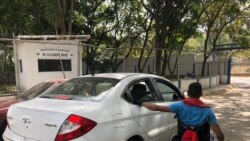Un hombre en silla de rueda se sujeta a un carro para poder recorrer la ciudad de Caracas, en Venezuela. Foto: Adriana Nuñez Rabascall/ VOA.