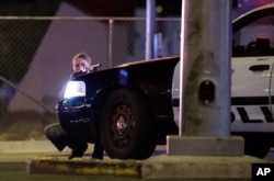En esta foto del 1 de octubre de 2017, un policía se cubre detrás de su patrulla durante el tiroteo desde el hotel Mandalay Bay a un concierto de música country, que dejó 58 personas muertas en el evento considerado el peor tiroteo masivo en la historia reciente de EE.UU. El asesino se suicidó.