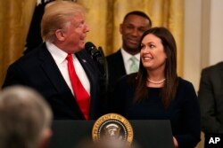 President Donald Trump welcomes White House press secretary Sarah Sanders to the stage as he pauses from speaking about second chance hiring to publicly thank the outgoing press secretary in the East Room of the White House, June 13, 2019, in Washington.