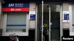 一名女士打开上海浦东发展银行开设在北京的一所支行的大门。（2011年7月6日）