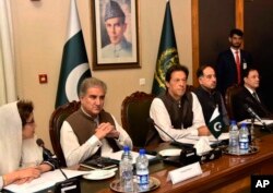 In this photo released by the Press Information Department, Pakistani Prime Minister Imran Khan, center, attends a briefing at the Foreign Ministry in Islamabad, Pakistan, Aug. 24, 2018. Pakistani Foreign Minister Shah Mehmood Qureshi is seen second from left.