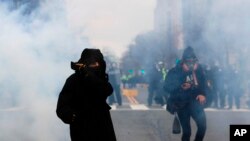Un manifestante protege su boca y nariz contra el gas disparado por la policía durante una manifestación después de la inauguración del presidente Donald Trump el viernes 20 de enero de 2017 en Washington.