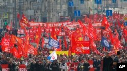 Manaifestantes portando banderas rojas marcha por las calles de Moscú en el Día Internacional del Trabajo el martes, 1 de mayo, de 2018.