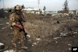An Afghan security forces member walks next to a crater caused by a suicide bomb attack in Kabul, Afghanistan, Nov. 29, 2018.