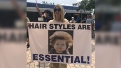 Una mujer sostiene un cartel con el lema "Los peinados también son esenciales" durante una protesta en Miami para pedir la reapertura de Florida durante la pandemia del coronavirus.