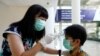A teacher checks a student with thermal scanner at school after Indonesia confirmed its first cases of coronavirus disease (COVID-19), in Tangerang near Jakarta, Indonesia, March 6, 2020. 