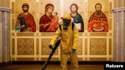Un especialista que usa equipo de protección personal rocía desinfectante mientras higieniza una capilla dentro del edificio de la estación de tren de Leningradsky, en Moscú, en medio del brote de la enfermedad del coronavirus, el 19 de octubre de 2021.