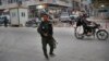 FILE - A member of the Kurdish internal security forces patrols a commercial street in Manbij, northern Syria, March 28, 2018. Manbij, a mixed Arab and Kurdish town of nearly 400,000, was freed from Islamic State militants in 2016 by YPG fighters with the backing of U.S. forces.