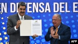 El presidente venezolano Nicolás Maduro recibe un certificado con el resultado electoral del referendo consultivo del domingo de manos del presidente del poder electoral, Elvis Amoroso, este lunes 4 de diciembre de 2023.