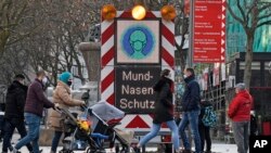 An electronic board reminds people to wear the mandatory face masks in a shopping street in Dortmund, Germany, Monday, Nov. 23, 2020.