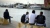 FILE - Unaccompanied minors from north Africa sit by the river Tiber, in Fiumicino, Italy, 30 kilometers (19 miles) west of Rome, April 21, 2016.