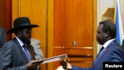 FILE - South Sudan's President Salva Kiir (L) and the country's rebel leader, Riek Machar, exchange signed peace agreement documents in Addis Ababa May 9, 2014.