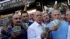 Businessmen holding U.S. dollars stand in front of a currency exchange office in response to the call of Turkish President Tayyip Erdogan on Turks to sell their dollar and euro savings to support the lira, in Ankara, Aug. 14, 2018.