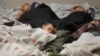 In this June 18, 2014, file photo, detainees sleep in a holding cell at a U.S. Customs and Border Protection, processing facility in Brownsville,Texas. 