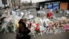 A woman lights a candle outside the kosher grocery where Amedy Coulibaly killed four people in a terror attack, in Paris, Jan. 20, 2015.