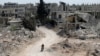 FILE - A man rides a motorbike past damaged buildings in the rebel-held town of Nairab, Idlib region, Syria, April 17, 2020. 