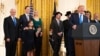 President Donald Trump holds up an executive order he signed to help combat anti-Semitism in the U. S., during a Hanukkah reception in the East Room of the White House, Dec. 11, 2019, in Washington. 