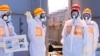Japan's Prime Minister Shinzo Abe (2nd R), wearing protective suit and mask, is briefed about tanks containing radioactive water by Fukushima Daiichi nuclear power plant chief Akira Ono (2nd L), as they stand near a tank (C, with railings painted red and 